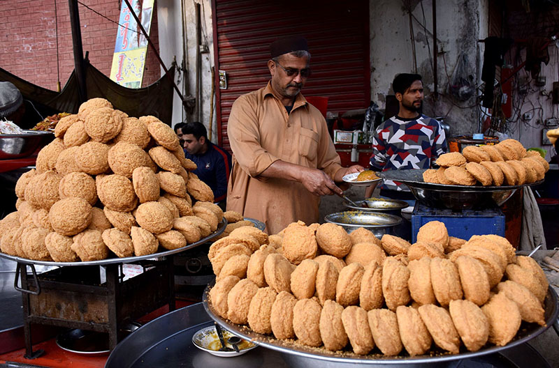 A vendor is selling the traditional food item “Laddu Peethi” to the customers on his roadside setup at local market