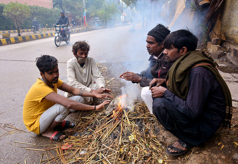 People sitting around the fire to keep them warm in a chilled weather during morning time