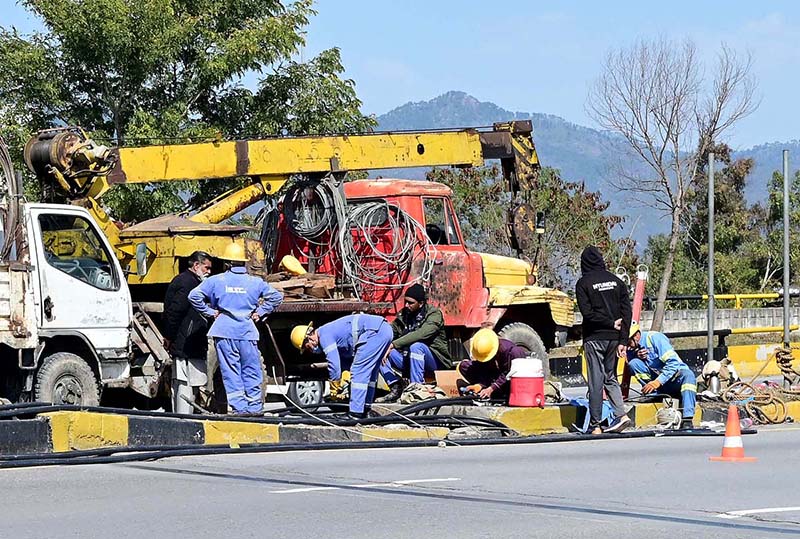 Workers busy repairing electricity supply line at Srinagar Highway in the Federal Capital.