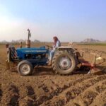 A farmer ploughing field with the help of tractor near Lahore Road