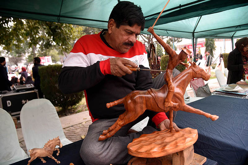 A craftsman is making a horse model by hand on the occasion of Winter Festival at Al Hamra Cultural Complex