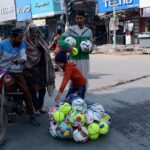 A vendor selling footballs to earn his livelihood