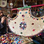 An artisan decorates hand fan at his workplace at Dabgari area.