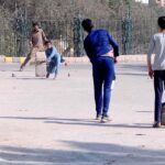 Children playing cricket at roadside