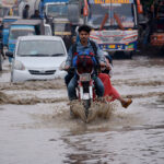 Vehicles passing through rain water accumulated on the Korangi road during heavy rain that experienced in the city