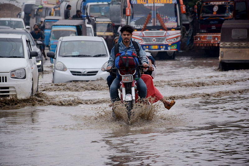 Vehicles passing through rain water accumulated on the Korangi road during heavy rain that experienced in the city