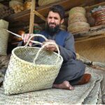 A craftsman busy in making a basket from dried date palm leaves at his shop in the Dabgari area