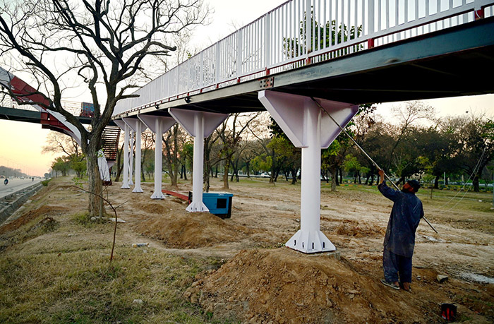 Worker busy paint on the pedestrian bridge at Srinagar Highway in the Federal Capital.