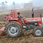 A young farmer ploughing field with the help of tractor