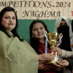 Principal, Miss. Najam UN Nisa giving winning trophy to the student during inter collegiate Competition of milli naghma 2024 at IMCG Bhara Kahu