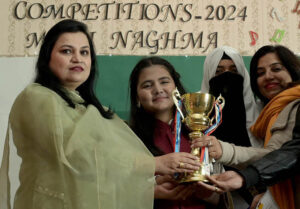 Principal, Miss. Najam UN Nisa giving winning trophy to the student during inter collegiate Competition of milli naghma 2024 at IMCG Bhara Kahu
