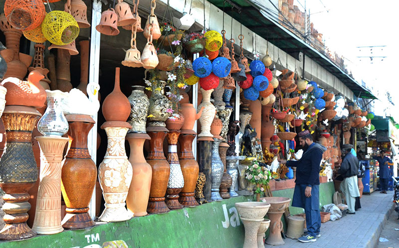 A shopkeeper is attracting customers with decorative items made of clay