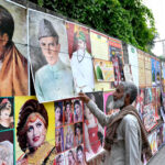An elderly man is decorating printed pictures on the wall to earn a living for children in the Provincial Capital city