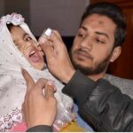 A health worker administering polio drops to child at the Railway Station