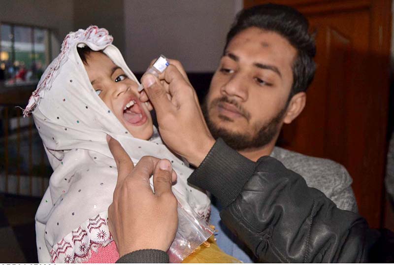 A health worker administering polio drops to child at the Railway Station