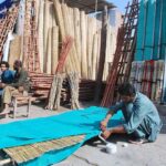 Artisan preparing traditional curtains on roadside.