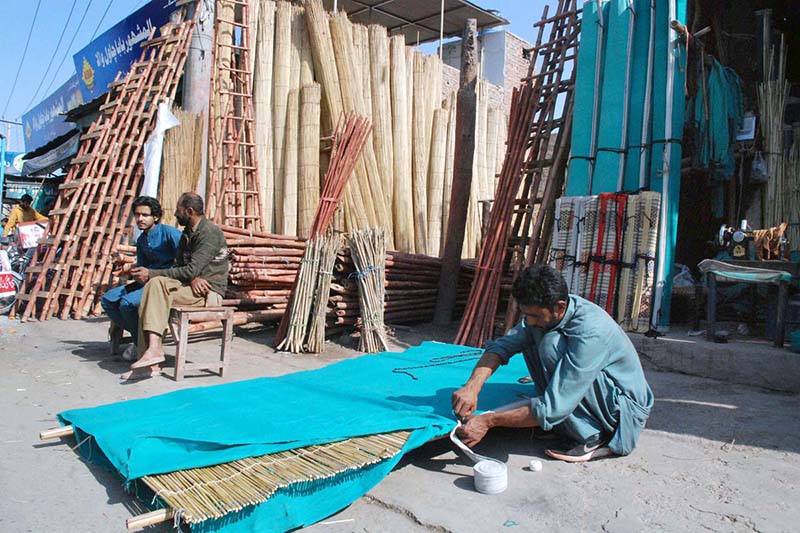 Artisan preparing traditional curtains on roadside.