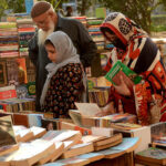 People selecting and purchasing old books from a roadside setup at Mall Road