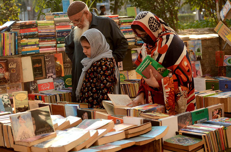 People selecting and purchasing old books from a roadside setup at Mall Road