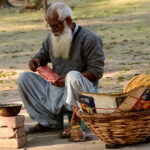 An elderly person is selling the traditional food item paapar to the customers on his roadside setup