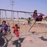 Gypsy girls enjoy swing at site area