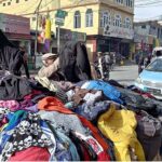People busy in selecting and purchasing second hand jackets from the roadside vendor