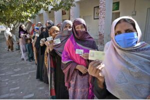 Women showing their identity card while standing in queue to cast their vote in polling station during General Election-2024