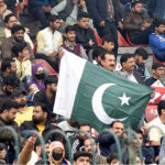 A man is waving the flag of Pakistan during the PSL-T20 match in the Gaddafi Stadium