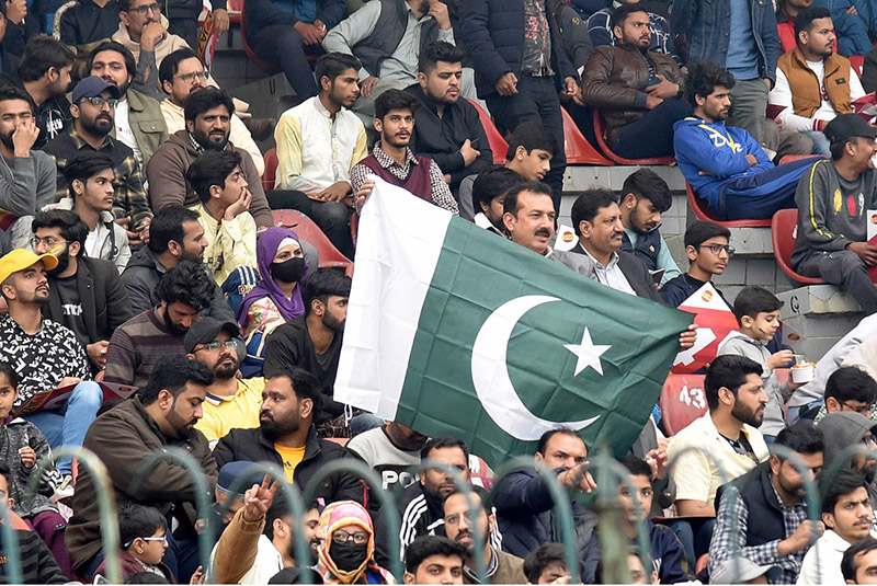 A man is waving the flag of Pakistan during the PSL-T20 match in the Gaddafi Stadium
