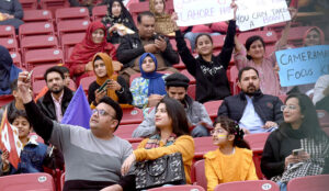A man is waving the flag of Pakistan during the PSL-T20 match in the Gaddafi Stadium