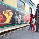 Passengers viewing banner installed on a train to mark Kashmir Solidarity Day at Cantt Railway Station