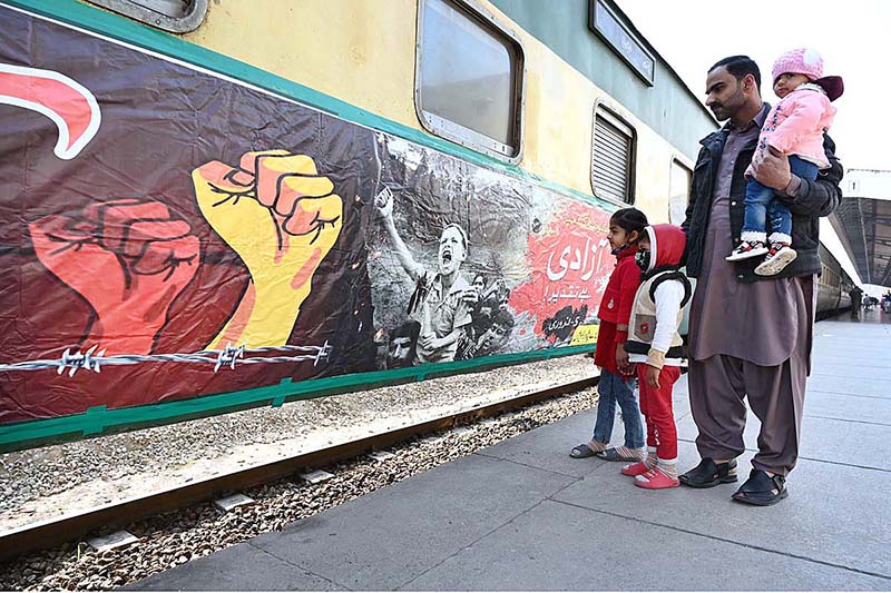 Passengers viewing banner installed on a train to mark Kashmir Solidarity Day at Cantt Railway Station