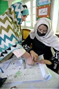 Women showing their identity card while standing in queue to cast their vote in polling station during General Election-2024
