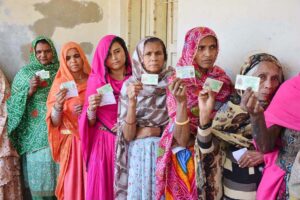 Women voters showing identity cards while standing in queue waiting for their turn to cast vote in polling station during General Election-2024