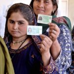 Women voters showing identity cards while standing in queue waiting for their turn to cast vote in polling station during General Election-2024