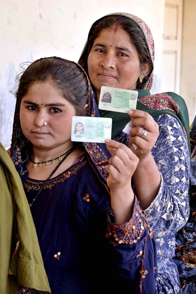 Women voters showing identity cards while standing in queue waiting for their turn to cast vote in polling station during General Election-2024