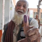An elderly person shows his thumb after casting his vote at polling station during the General Election-2024.