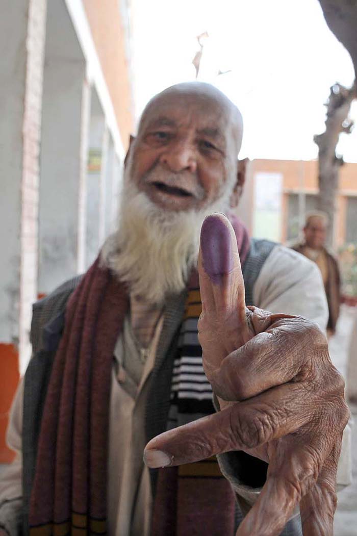 An elderly person shows his thumb after casting his vote at polling station during the General Election-2024.