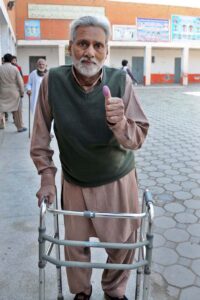 An elderly person shows his thumb after casting his vote at polling station during the General Election-2024.