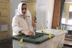 Polling officer marks the thumb of a woman voter before issuing ballot paper at a polling station during the General Election-2024.