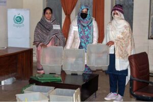 Polling officer marks the thumb of a woman voter before issuing ballot paper at a polling station during the General Election-2024.