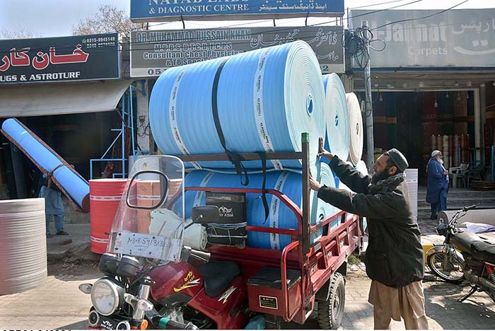A labourer loading foamic sheets on loader rickshaw at Said Pur Road.
