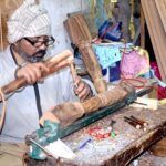 A carpenter making wooden furniture at his setup on Said Pur Road.