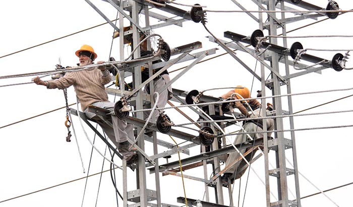 WAPDA workers busy in installing new electricity cables on pylons at Tarlai.