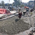 Labourers busy in repairing work of damaged road at Commercial Market.