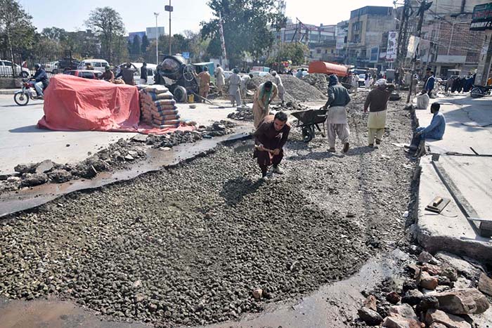 Labourers busy in repairing work of damaged road at Commercial Market.