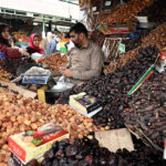 People purchasing different food items for upcoming Holy Month of Ramadan displayed by vendor at weekly bazaar