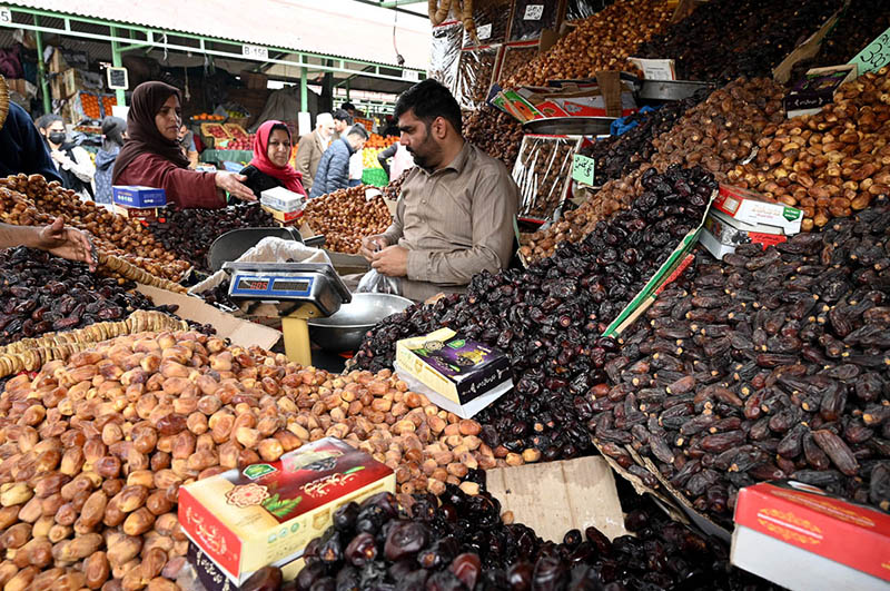 People purchasing different food items for upcoming Holy Month of Ramadan displayed by vendor at weekly bazaar