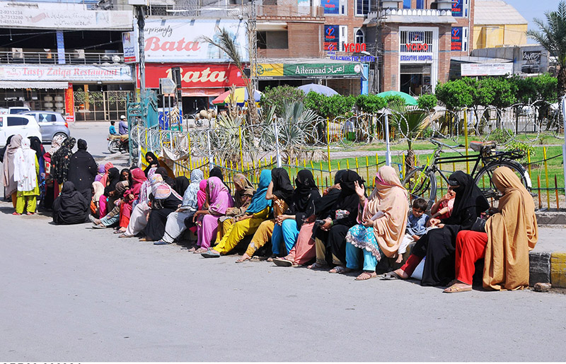 Women sitting in a queue waiting for the subsidized flour bags truck at Ghanta Ghar.