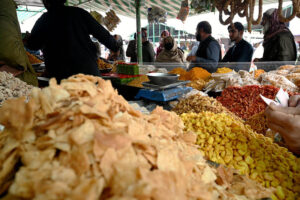 People purchasing different food items for upcoming Holy Month of Ramadan displayed by vendor at weekly bazaar